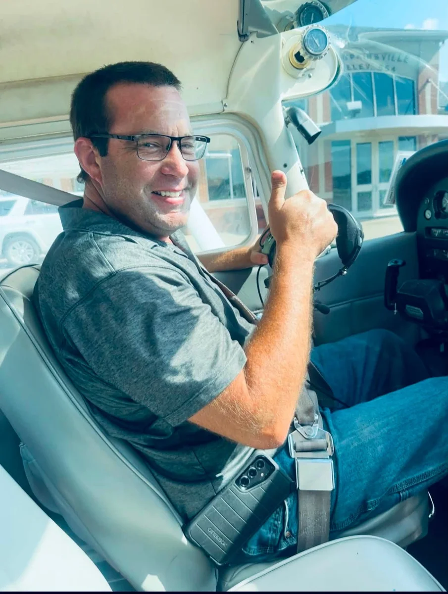 Travis smiling and giving a thumbs-up in a Hangar One airplane